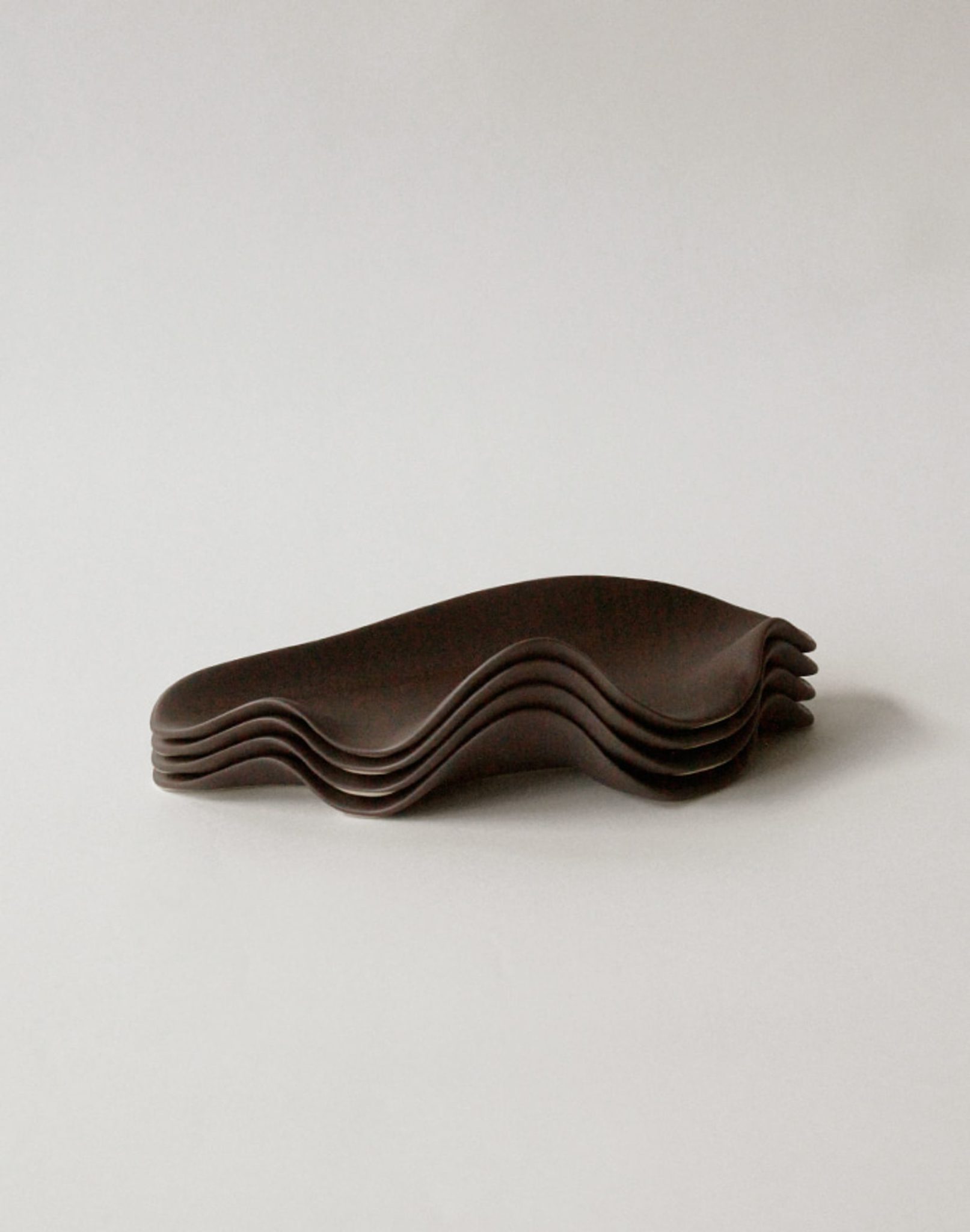 A stack of four NR Ceramics HIN Leaf Plates with wavy edges is arranged neatly on a light grey background, highlighting the stylish and eco-friendly tableware from NR Ceramics.