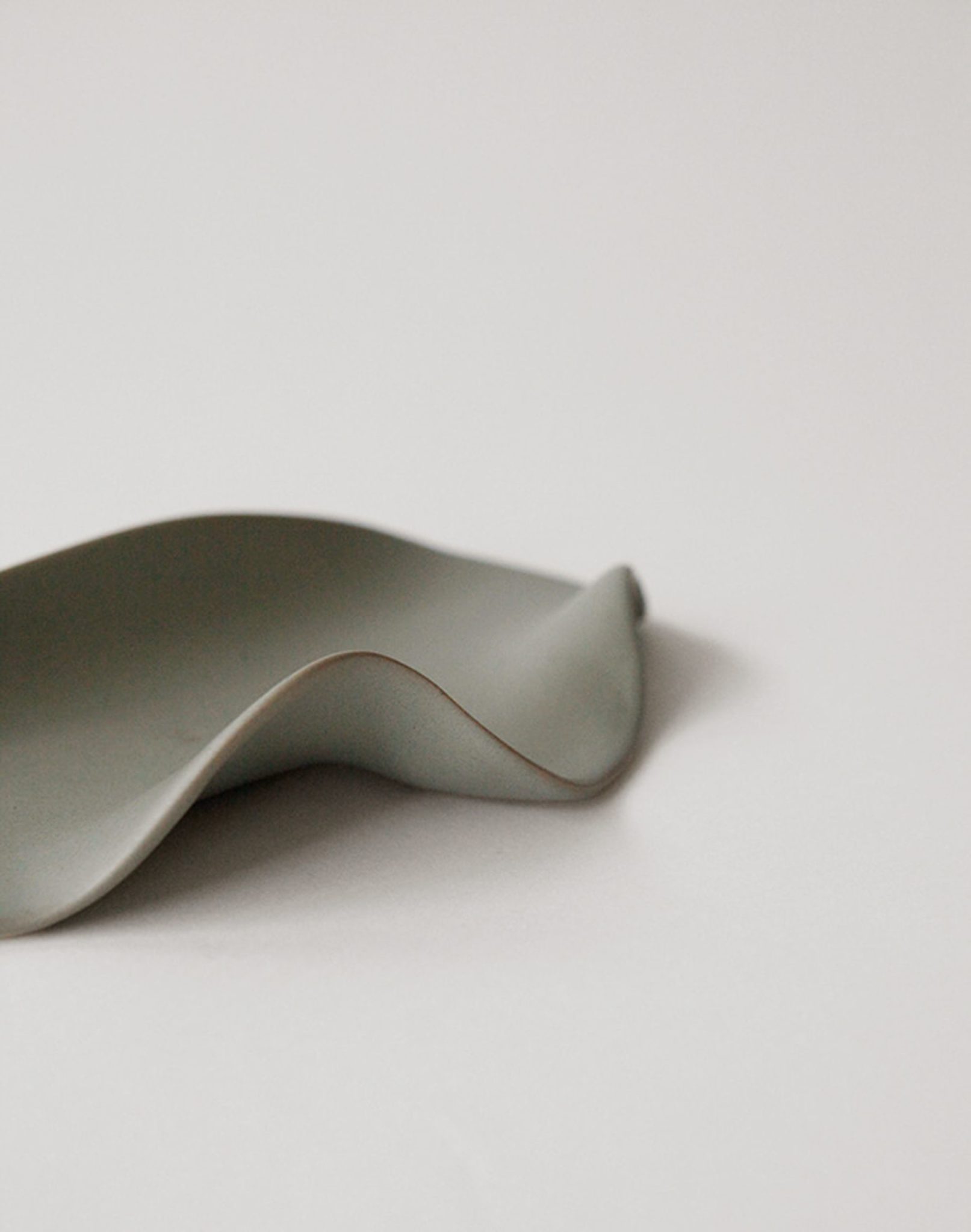 A minimalist photo of the NR Ceramics HIN Leaf Plate by NR Ceramics on a plain white background, featuring soft lighting and smooth curves for a modern look—ideal as versatile multi-functional tableware.