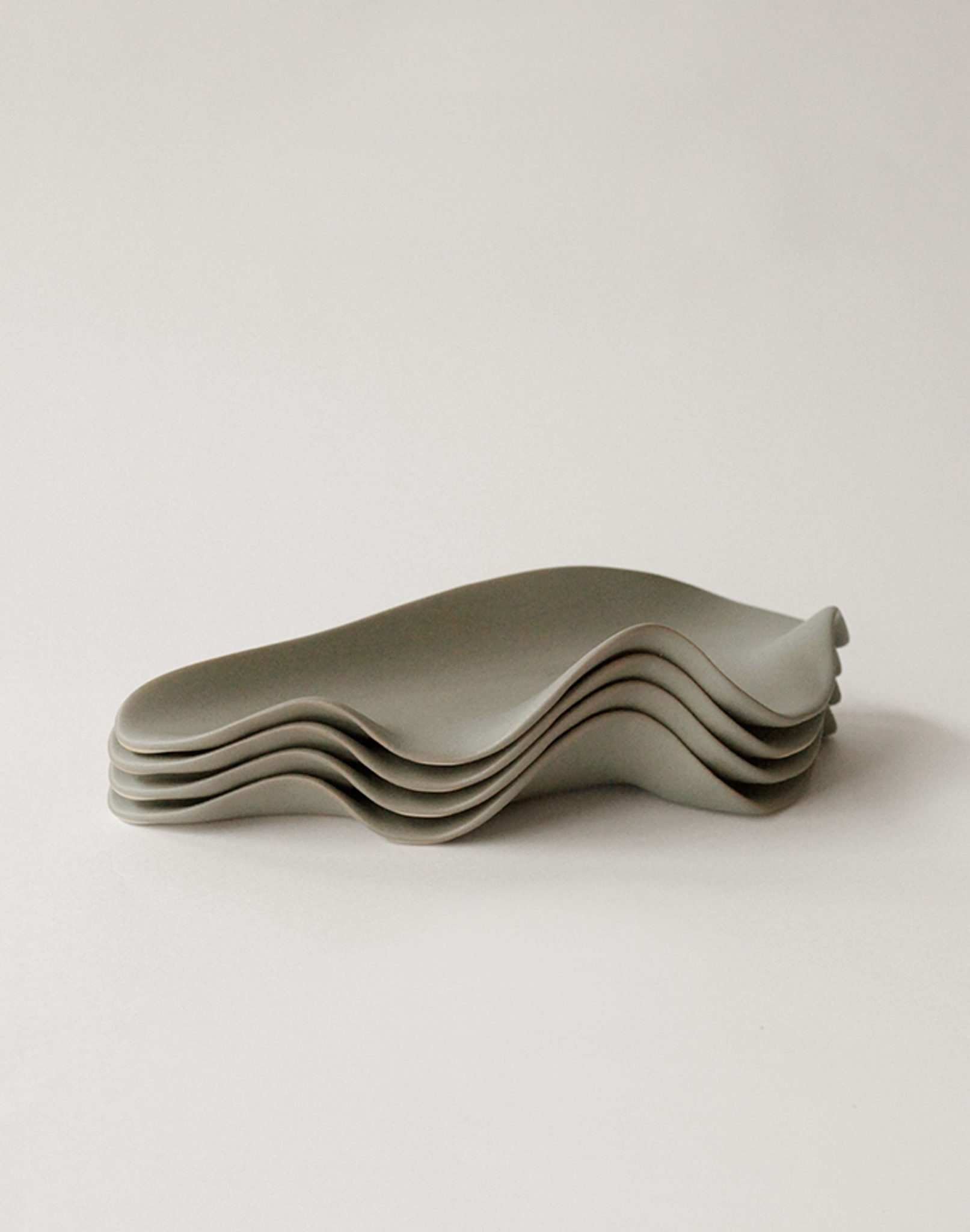 A set of five NR Ceramics HIN Leaf Plates with modern, minimalist design and wavy edges, arranged neatly on a light surface—ideal as versatile tableware for any occasion.