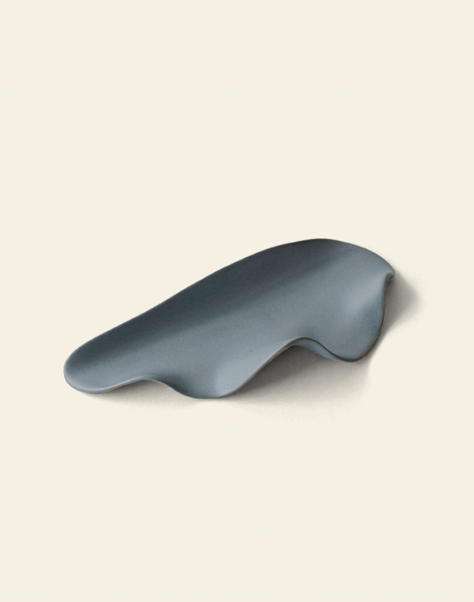 A smooth, abstract gray object with an organic shape sits on a plain background—reminiscent of the NR Ceramics HIN Leaf Plate by NR Ceramics, known for its sculptural form and versatile tableware design.