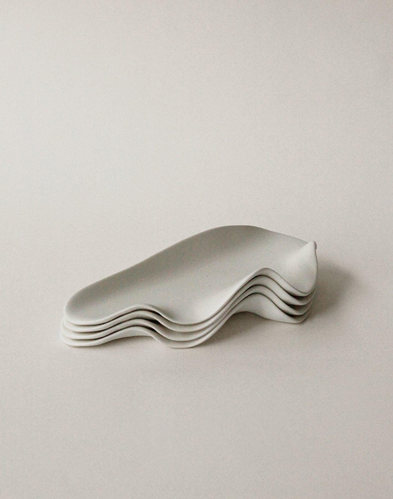 Five NR Ceramics HIN Leaf Plates with smooth, wavy edges are stacked neatly, highlighting this elegant, multi-functional tableware set from NR Ceramics against a plain white background.