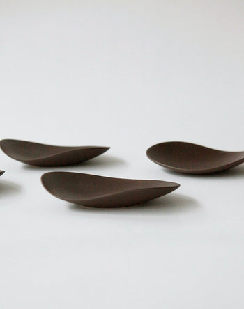 The NR Ceramics HIN Pebble Plate S by NR Ceramics sits on a plain white surface. Its smooth, minimalist form with rounded edges and matte finish adds a modern touch—ideal for pairing with contemporary tableware.