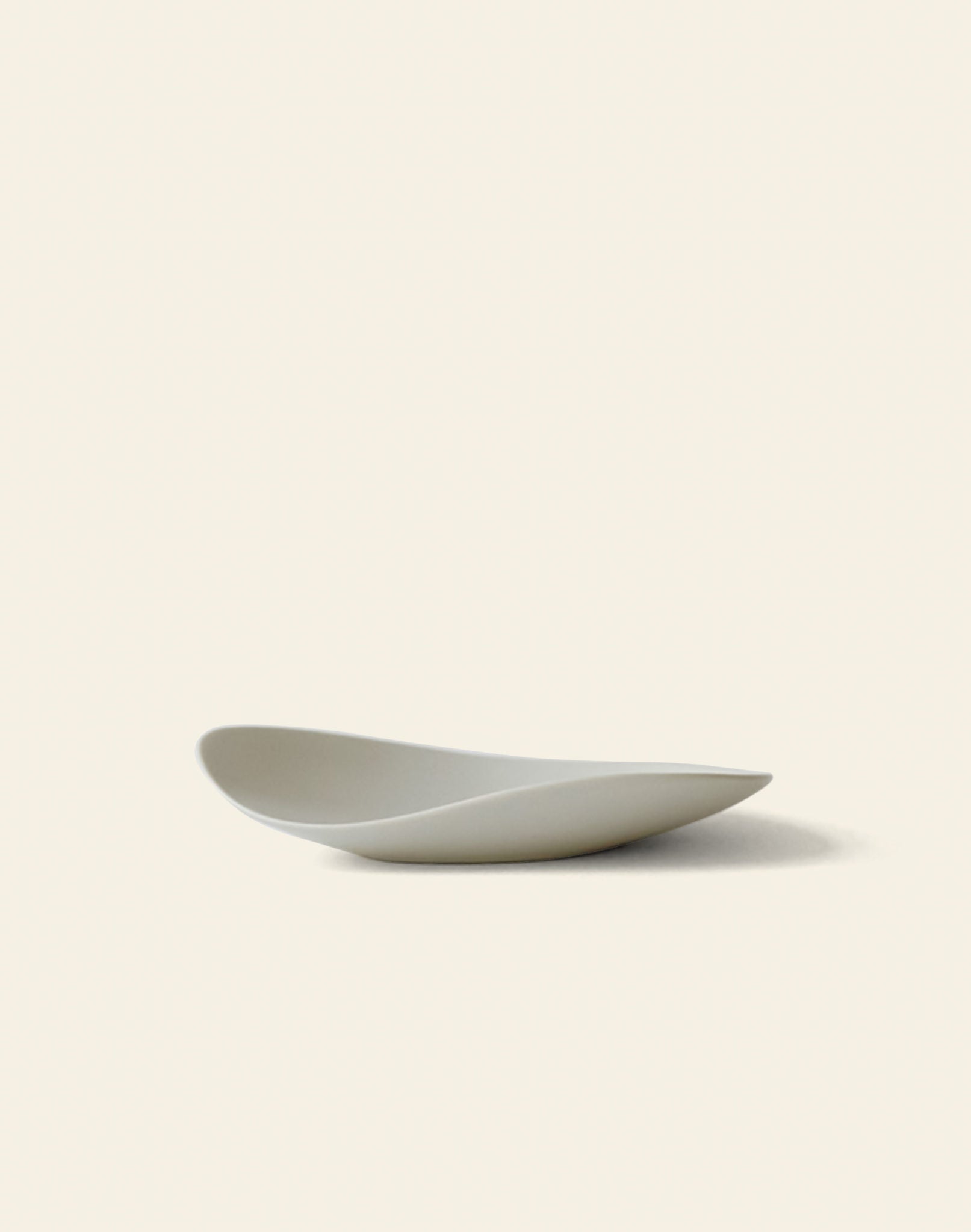 The NR Ceramics HIN Pebble Plate S is a minimalist white tableware piece with smooth, curved edges, shown on a plain light background and casting a soft shadow to the right.