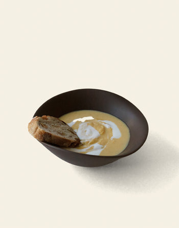 The NR Ceramics HIN Soup Bowl by NR Ceramics, filled with creamy soup and rustic bread on the side, sits against a plain background—versatile tableware perfect for any dining setting.