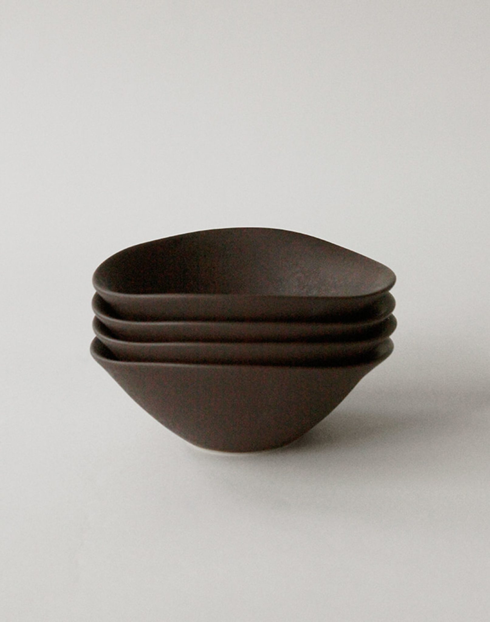 Four dark brown NR Ceramics HIN Soup Bowls are stacked neatly on a plain white background, highlighting versatile, minimalist tableware by NR Ceramics for any setting.