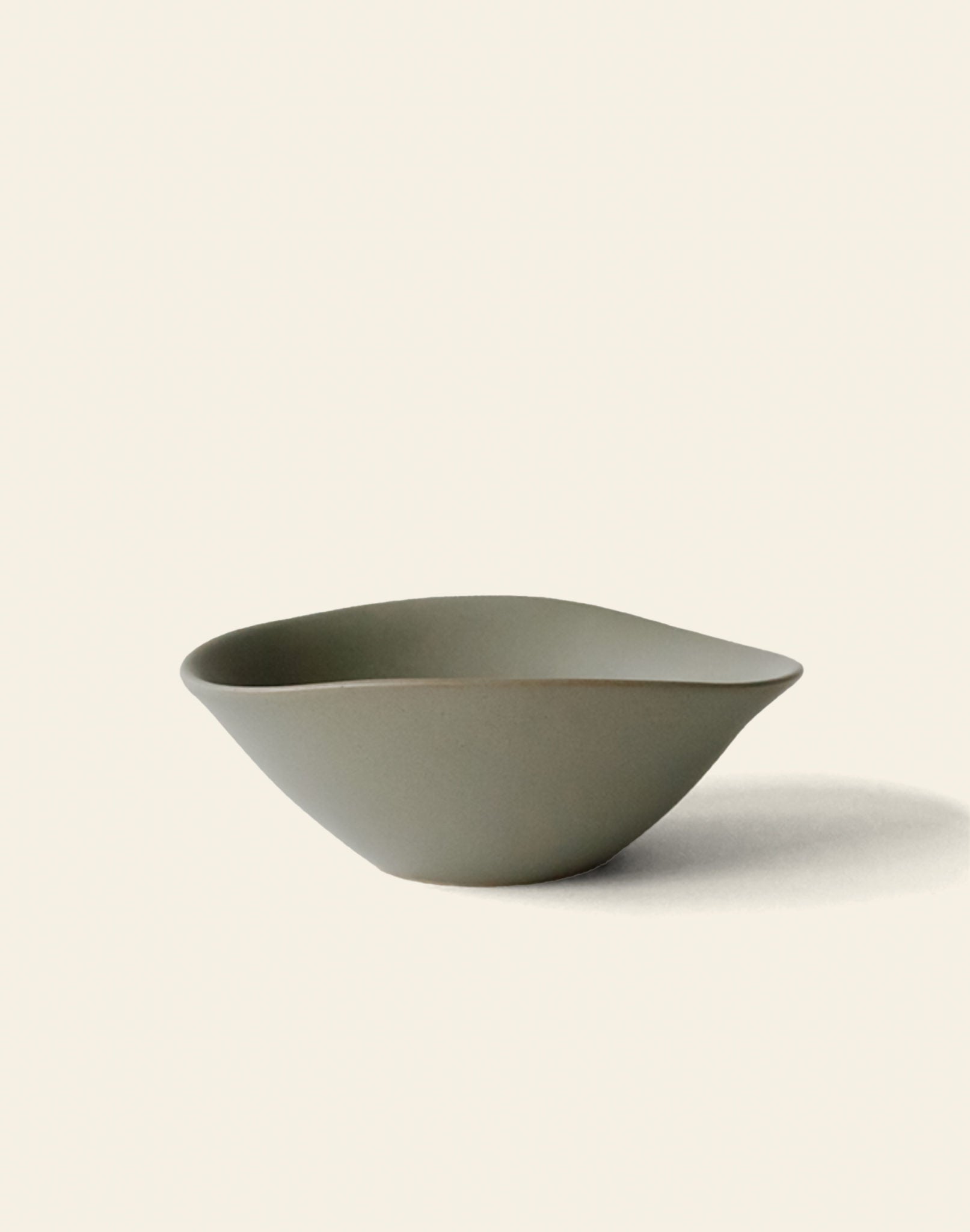 The NR Ceramics HIN Soup Bowl by NR Ceramics features a simple matte olive-green finish, an organic uneven shape, and is perfect as versatile tableware for everyday dining.