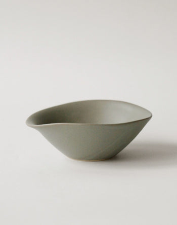 The NR Ceramics HIN Soup Bowl is a matte, olive-green ceramic piece with an asymmetric, organic shape—versatile tableware from NR Ceramics, ideal for modern dining.