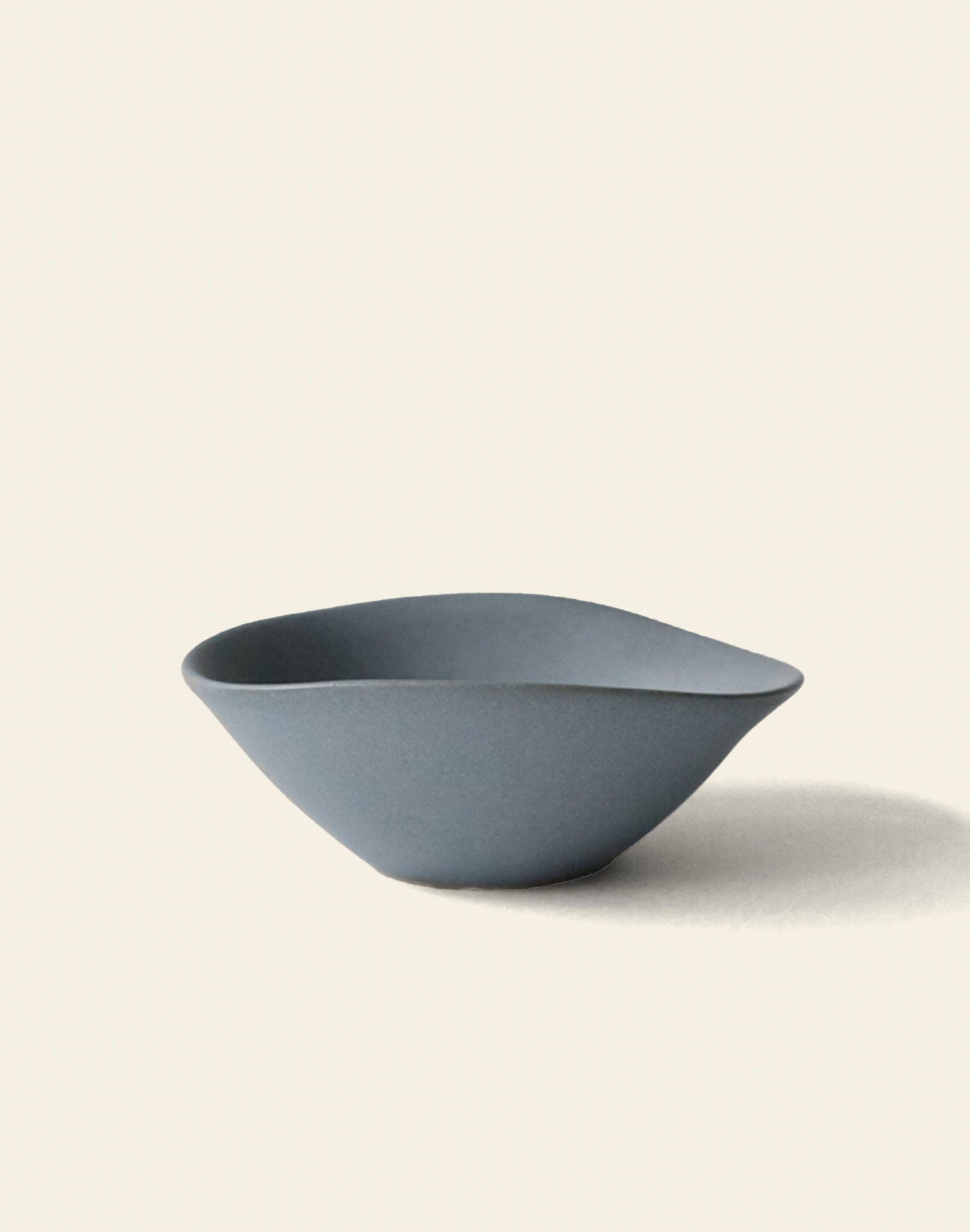 The NR Ceramics HIN Soup Bowl by NR Ceramics features a minimalist, matte blue finish and slightly irregular, organic shape, shown on a light neutral background with a soft shadow.