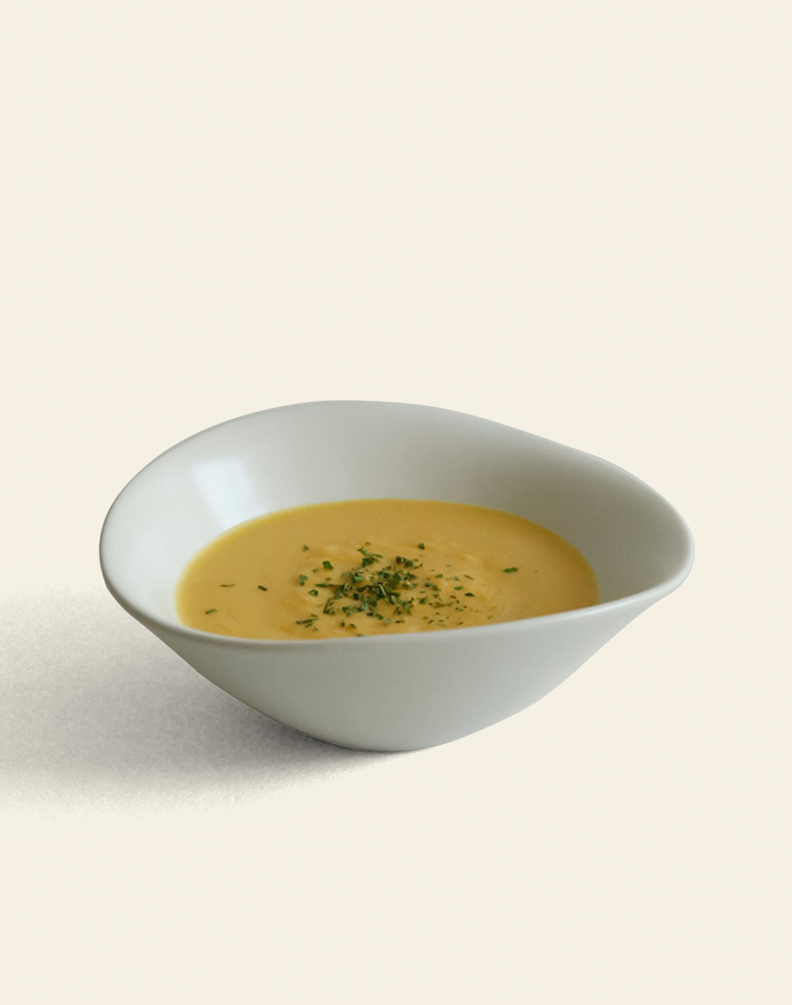 A NR Ceramics HIN Soup Bowl filled with creamy yellow soup and topped with green herbs, set against a simple background—an ideal way to highlight the versatile tableware from NR Ceramics.