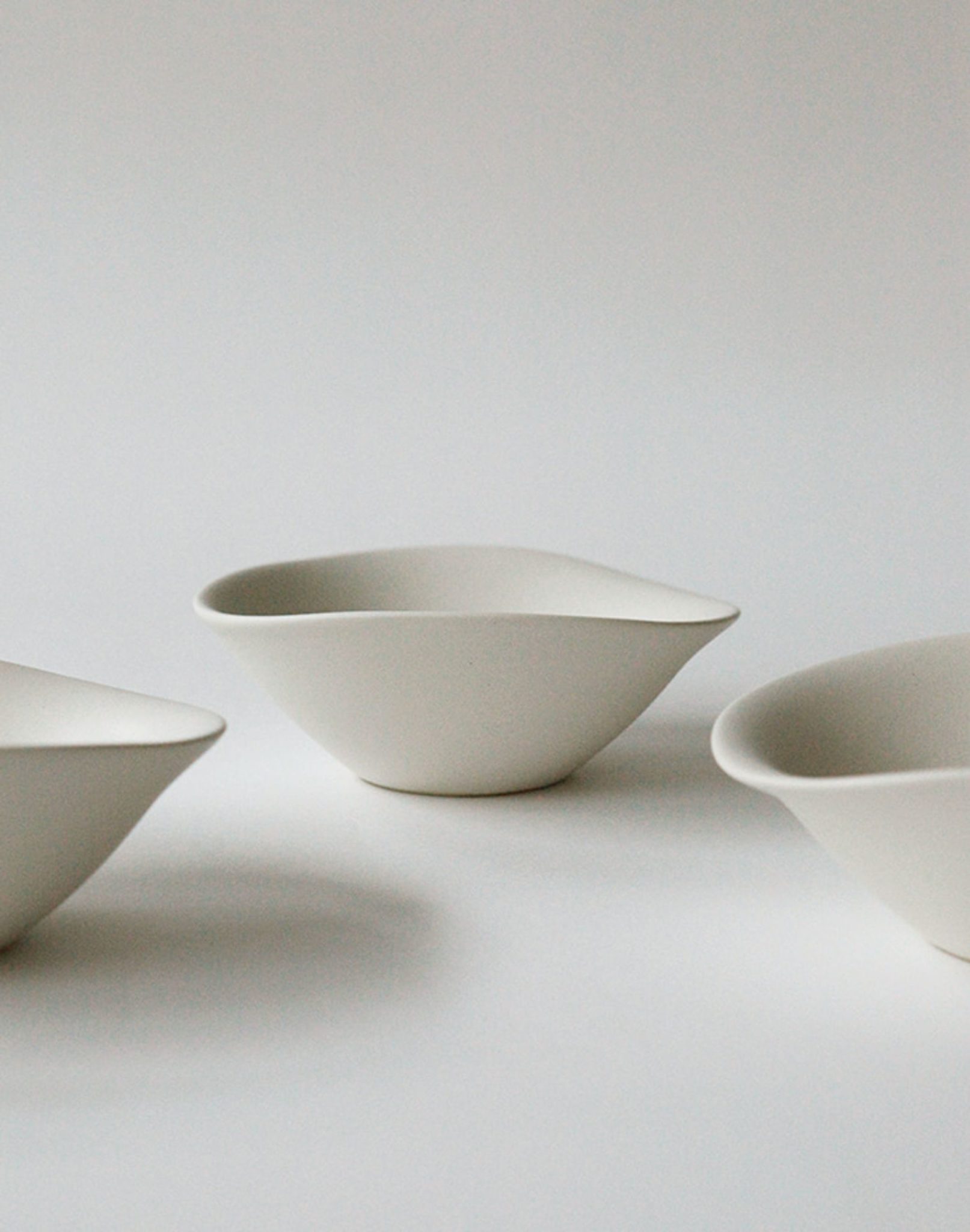 The NR Ceramics HIN Soup Bowl by NR Ceramics, with smooth white asymmetric curves, enhances any table with its minimalist design—ideal as a soup bowl or for daily use in a modern setting.