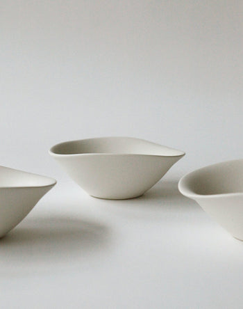 The NR Ceramics HIN Soup Bowl by NR Ceramics, with smooth white asymmetric curves, enhances any table with its minimalist design—ideal as a soup bowl or for daily use in a modern setting.