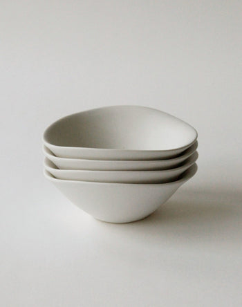 Four matte white NR Ceramics HIN Soup Bowls are stacked neatly on a white surface, showcasing versatile, modern tableware from NR Ceramics—ideal for soup or everyday use in a minimalistic setting.