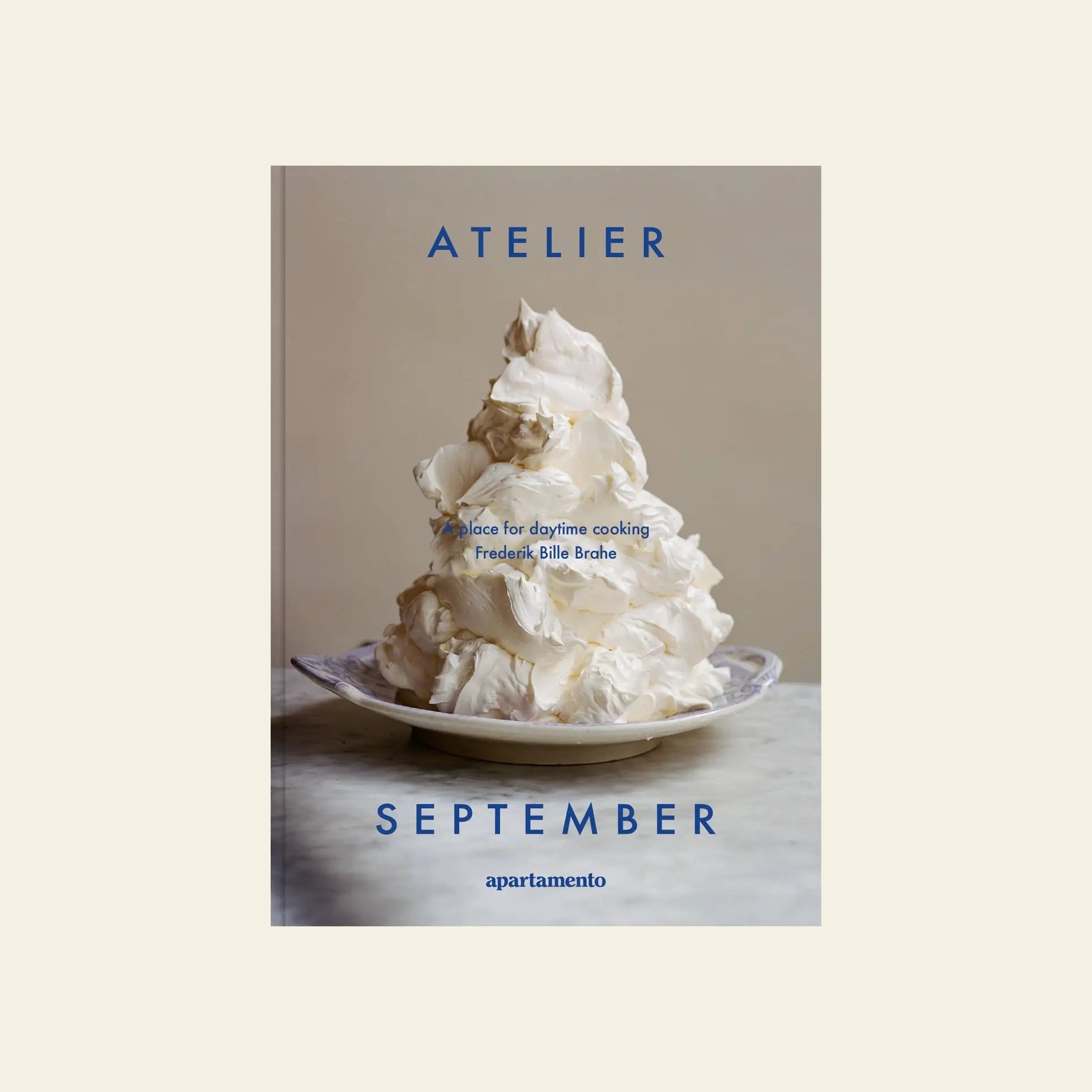 Apartamento’s Atelier September: A Place for Daytime Cooking cookbook features a cover with a plate topped by whipped cream, reflecting the inventive and inviting vibe of Frederik Bille Brahe’s Copenhagen restaurant.
