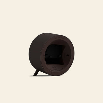 The Newgate Fred Alarm Clock by Newgate features a dark brown, round, mid-century modern casing with two small legs—ideal for your bedside table. Its back panel houses the battery compartment and product details on a beige background.