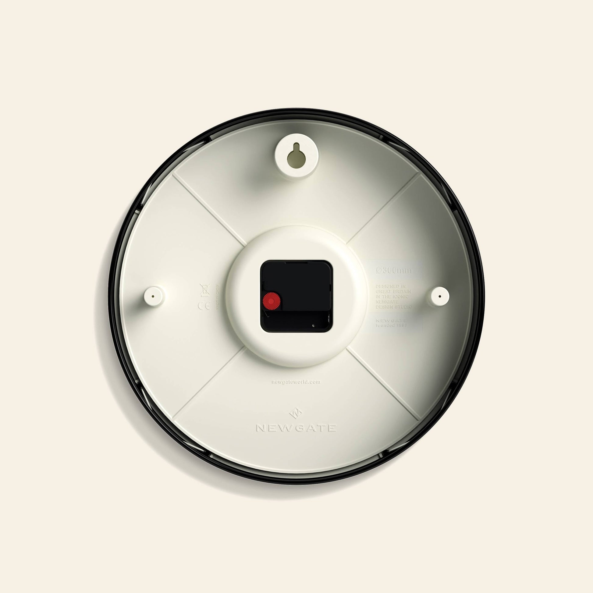 The image shows the back of the Newgate Luggage Wall Clock with a black frame, white interior, central battery compartment, two wall-mounting holes, and embossed Newgate branding near the bottom for a retro touch.