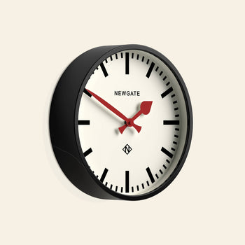 The Newgate Luggage Wall Clock features a black frame, white face, bold black hour markers, and a red second hand. This station-style wall clock by Newgate adds retro charm and stylish appeal to any room.