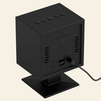 The Newgate Monolith LCD Alarm Clock by Newgate is a black, box-shaped clock with top buttons and a rear cord, shown on a square stand against a plain background.