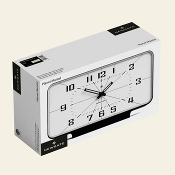 Newgate Planet Mantel Clock: A rectangular white mantel clock with bold black Arabic numerals and hands, featuring a retro minimalist black-and-white design. Shown in packaging labeled NEWGATE and Planet Mantel.