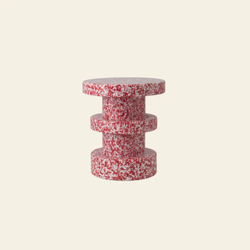 The Normann Copenhagen Bit Stool Stack features a small, modern cylindrical design with a red-and-white speckled texture, serving as both a side table and versatile seat against a plain light beige background.