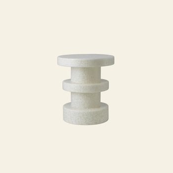 The Normann Copenhagen Bit Stool Stack by Normann Copenhagen features three stacked cylinders in textured white, offering modern, multifunctional style as a side table or extra seat—shown here against a plain beige background.