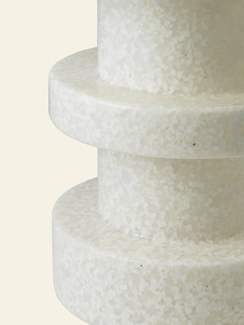 Close-up of the Normann Copenhagen Bit Stool Stack by Normann Copenhagen, featuring two stacked, circular white layers with a textured, speckled surface, set against a plain beige background for versatile seating options.