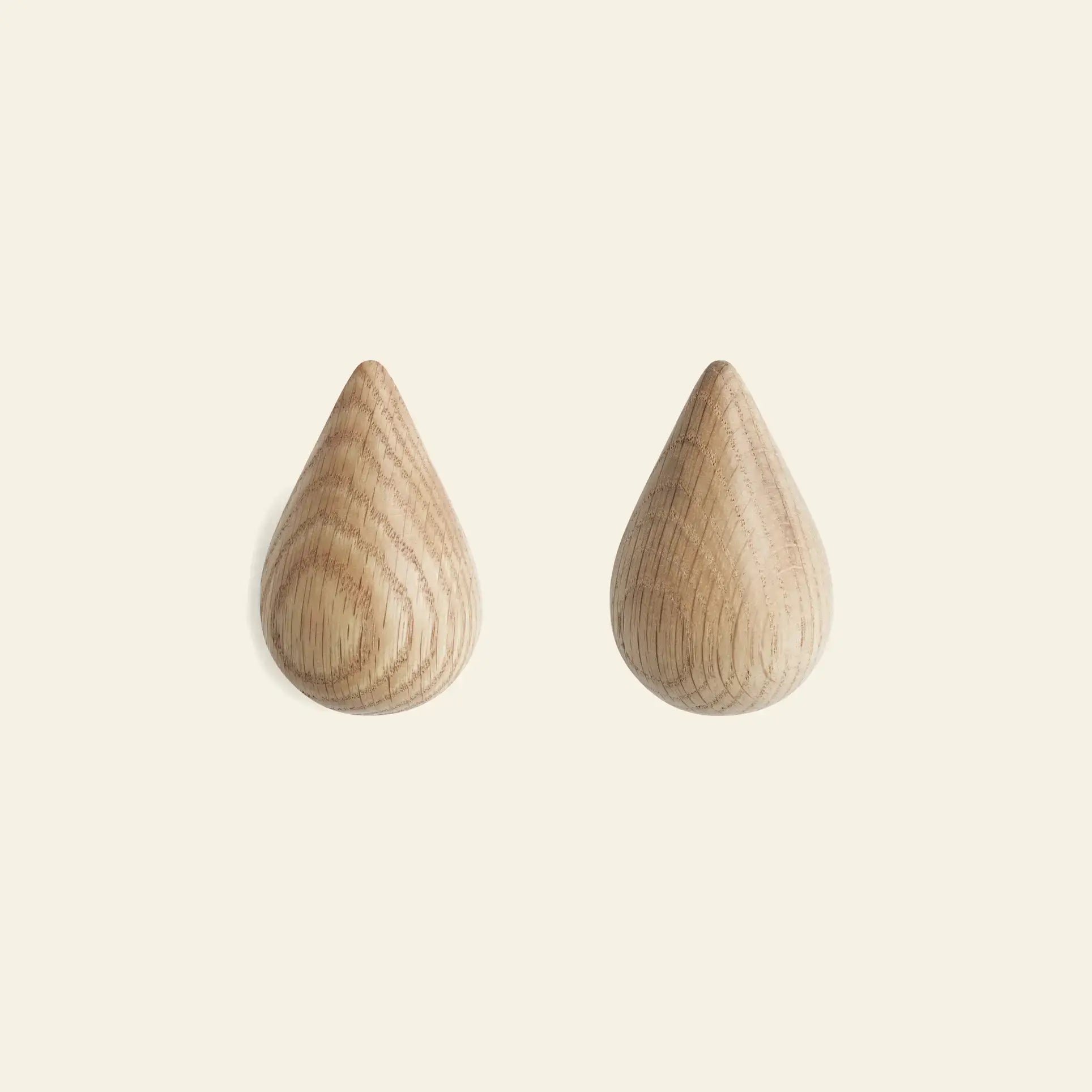 The Normann Copenhagen Dropit Hooks Small, Set of 2, are shown side by side on a light background, highlighting their elegant drop-shaped design in either oak or dark walnut by Normann Copenhagen.
