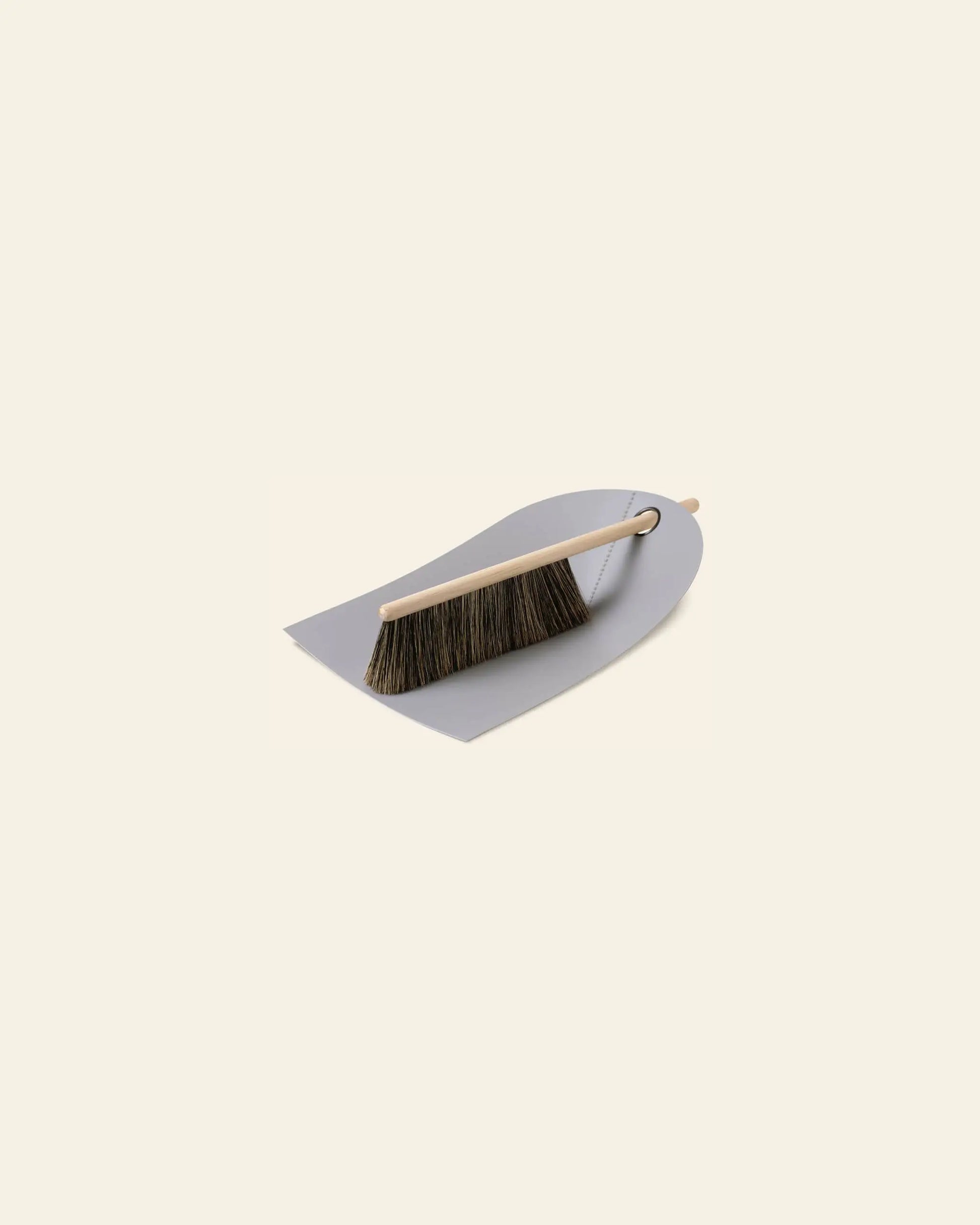 The Normann Copenhagen Dustpan & Broom features an ergonomic design with a wooden-handled brush and dark bristles resting neatly on the compact dustpan by Normann Copenhagen.
