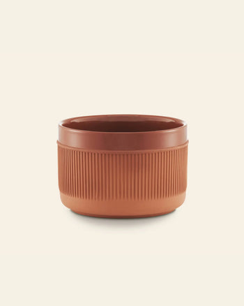 The Normann Copenhagen Junto Bowl, 15cm, features a round, rustic terracotta design with vertical ridges, ideal for enhancing your dinner table style.