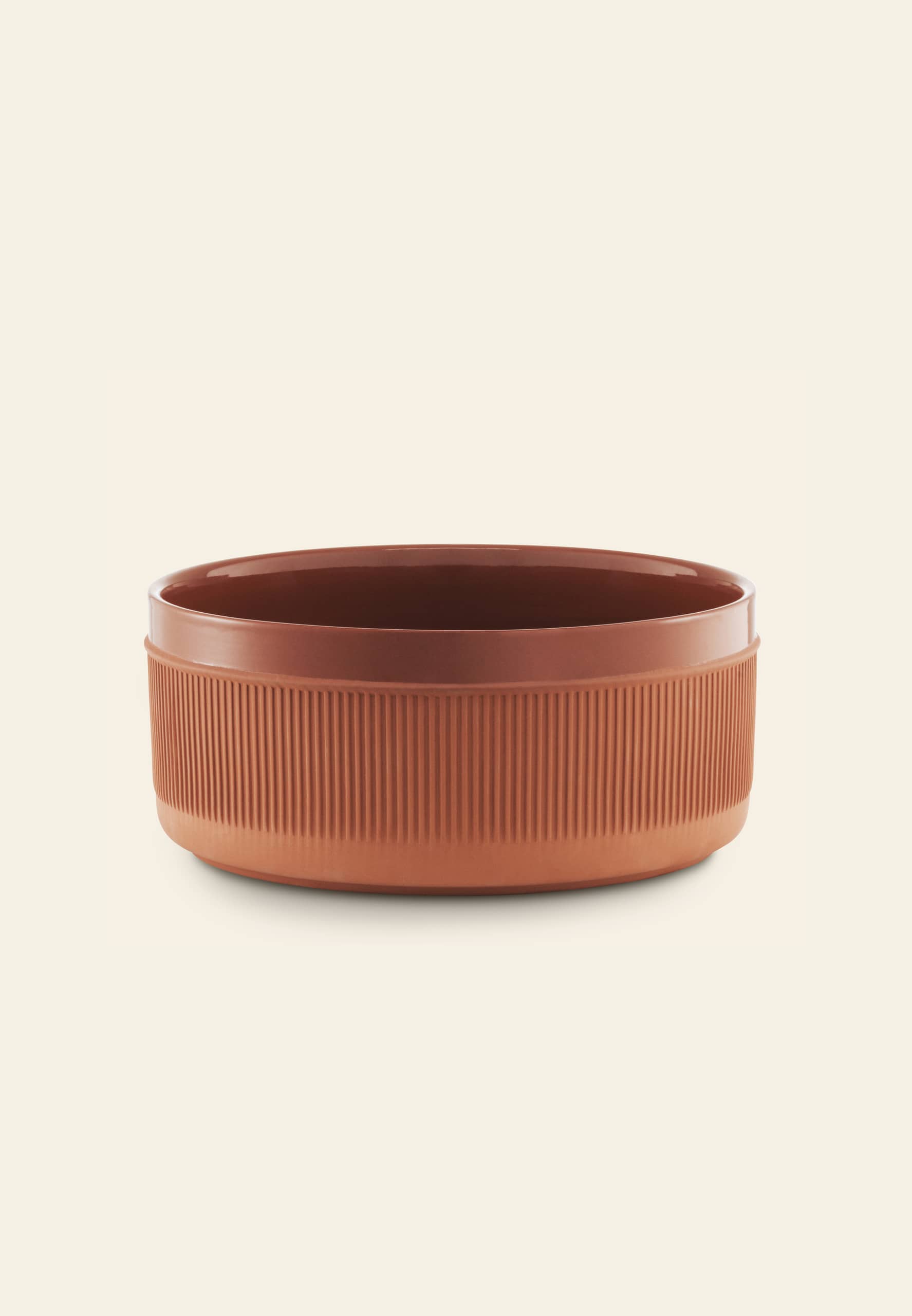 The Normann Copenhagen Junto Bowl, 24cm, features a round, rustic terracotta design with vertical grooves on the exterior, shown against an off-white background.
