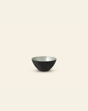 The Normann Copenhagen Krenit Bowl, 8.4cm, features a minimalist black exterior and light gray interior, set against a plain light beige background to showcase iconic Danish design.