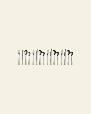 A set of Normann Copenhagen Cutlery Gift Box - 16 Pack by Normann Copenhagen is neatly arranged in pairs on a plain beige background, with the polished modern utensils evenly spaced and gleaming in the image.