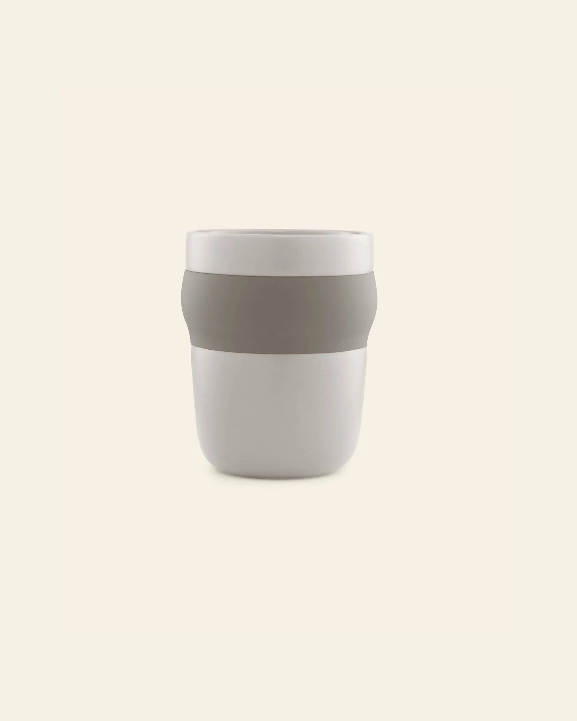 The Normann Copenhagen Obi Mug is a minimalist porcelain mug featuring a wide, light gray band around its middle, shown against a plain, light beige background.