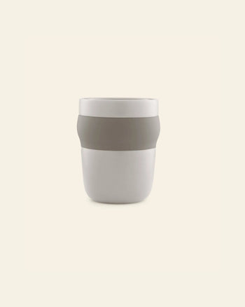 The Normann Copenhagen Obi Mug is a minimalist porcelain mug featuring a wide, light gray band around its middle, shown against a plain, light beige background.