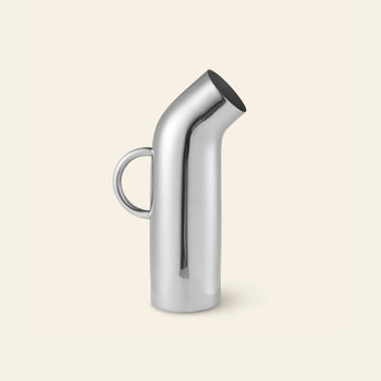 The Normann Copenhagen Pipe Pitcher by Normann Copenhagen features a modern stainless steel design with a curved spout and round handle, adding retro style to any kitchen. Shown against a plain, light beige background.