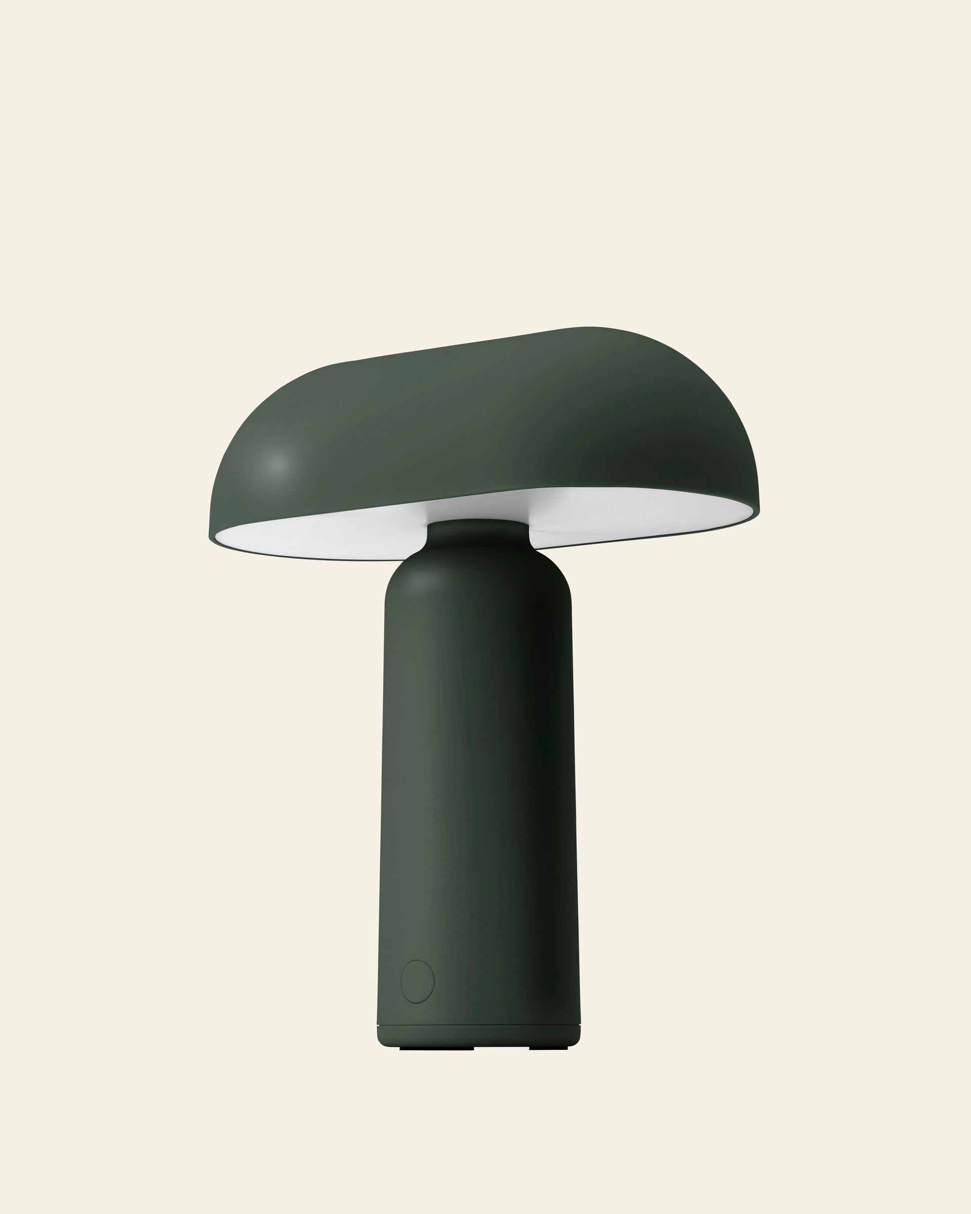 The Normann Copenhagen Porta Table Lamp features a modern dark green finish, with a rounded mushroom-like shade and cylindrical base, reflecting Normann Copenhagens design style, shown against a plain light beige background.