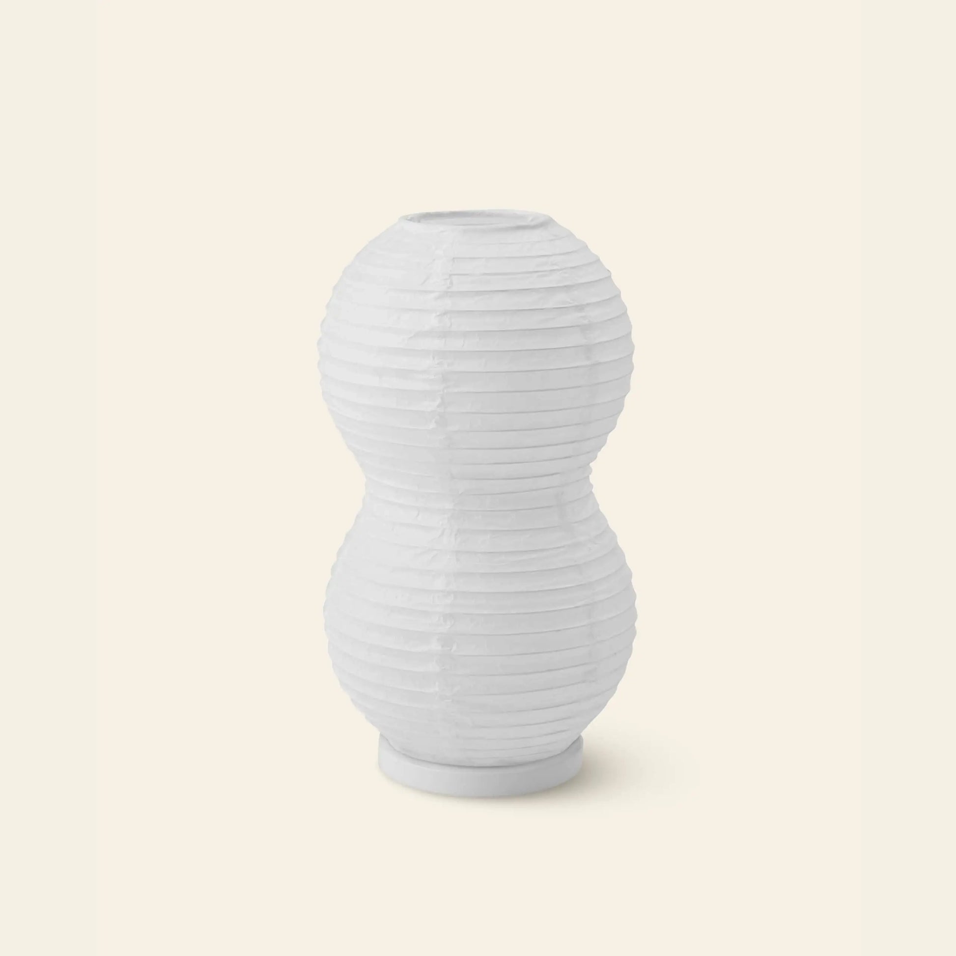 The Normann Copenhagen Puff Table Lamp Twist, featuring a white double-gourd shape with paper lantern-style horizontal ribbing, sits on a light beige background—ideal as a modern lighting fixture.