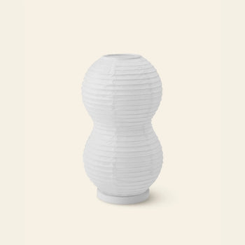 The Normann Copenhagen Puff Table Lamp Twist, featuring a white double-gourd shape with paper lantern-style horizontal ribbing, sits on a light beige background—ideal as a modern lighting fixture.
