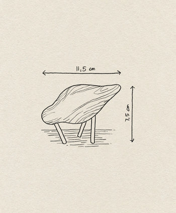A hand-drawn image of the Normann Copenhagen Shorebird Small Oak by Normann Copenhagen, featuring a minimalist design with four angled legs, shown with measurement arrows and labels: 11.5 cm wide and 7.5 cm tall.