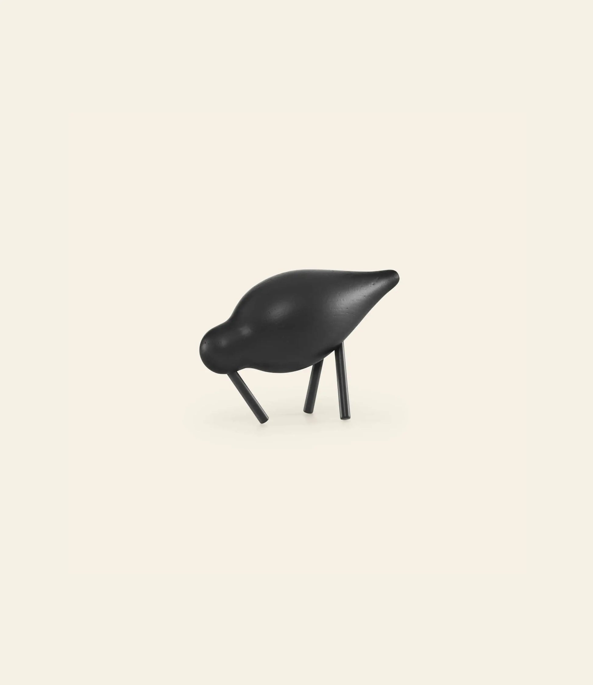 The Normann Copenhagen Shorebird Small Oak is a minimalist black figurine with a smooth, rounded body and angled oak legs, designed by Normann Copenhagen, displayed against a plain off-white background.