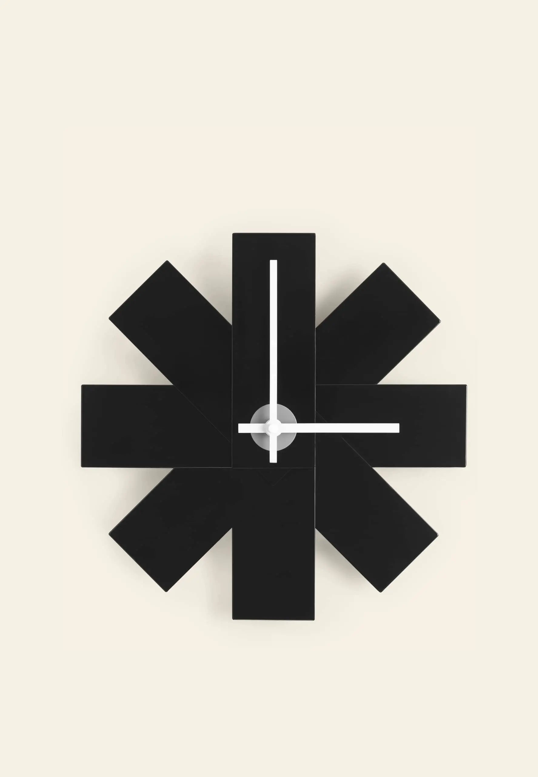 The Normann Copenhagen Watch Me Wall Clock by Normann Copenhagen features a modern, geometric black starburst design with simple white hands, ideal for adding minimalist style to your home decor against a light beige background.
