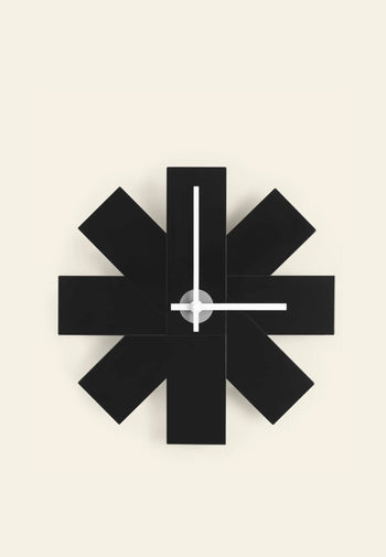 The Normann Copenhagen Watch Me Wall Clock by Normann Copenhagen features a modern, geometric black starburst design with simple white hands, ideal for adding minimalist style to your home decor against a light beige background.