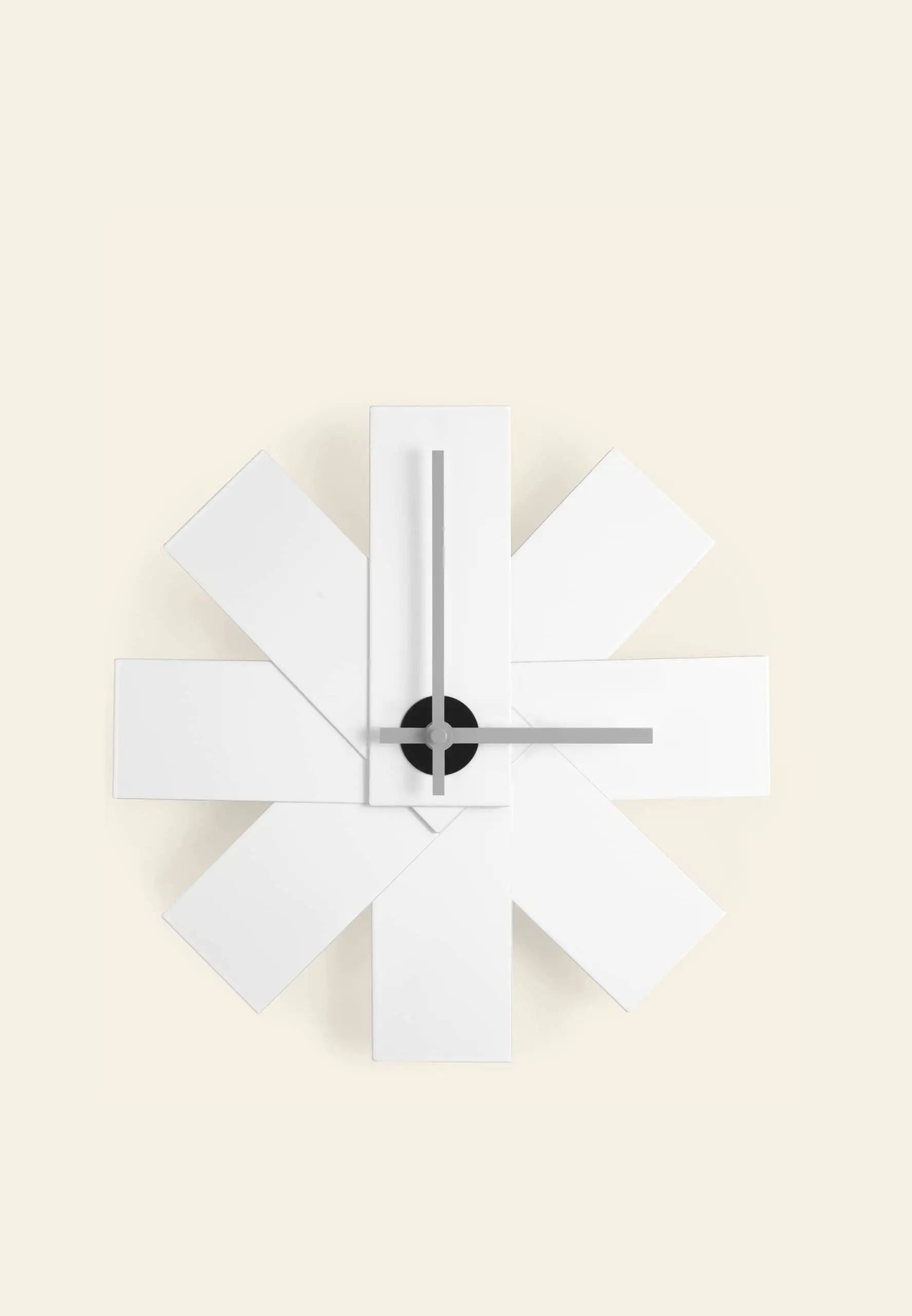 The Normann Copenhagen Watch Me Wall Clock by Normann Copenhagen features overlapping white rectangular panels in a starburst pattern, minimalist black hands, and a black center, creating a modern statement for home decor.