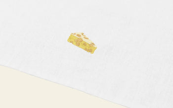 A small embroidered slice of apple pie with a lattice crust decorates the white linen and cotton Normann Copenhagen Yummy Tea Towel.