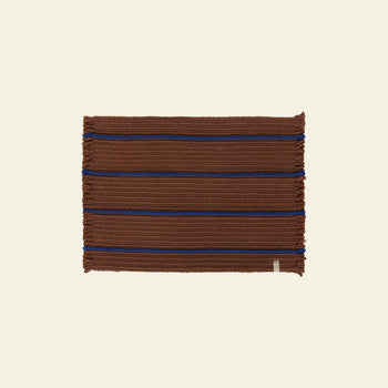 The OYOY Living Design Putki Recycled Doormat by OYOY Living Design features a rectangular brown woven design with blue stripes and ribbed detailing, made from recycled materials for sustainability, shown on a light beige background.