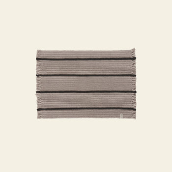 The OYOY Living Design Putki Recycled Doormat by OYOY Living Design features horizontal dark and light beige stripes, short-edge fringe, and is crafted from recycled materials. It is shown on a plain light background.