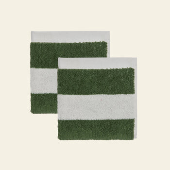 Two overlapping OYOY Living Design Raita Wash Cloths, pack of 2, made from organic cotton terry with green and white stripes, are placed on a light beige background.