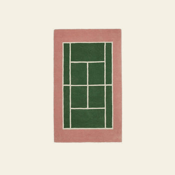 The OYOY Living Design Tennis Rug, crafted from a wool-cotton blend, features a thick pink border and geometric green center with white dividing lines, adding sporty flair to any plain off-white space.