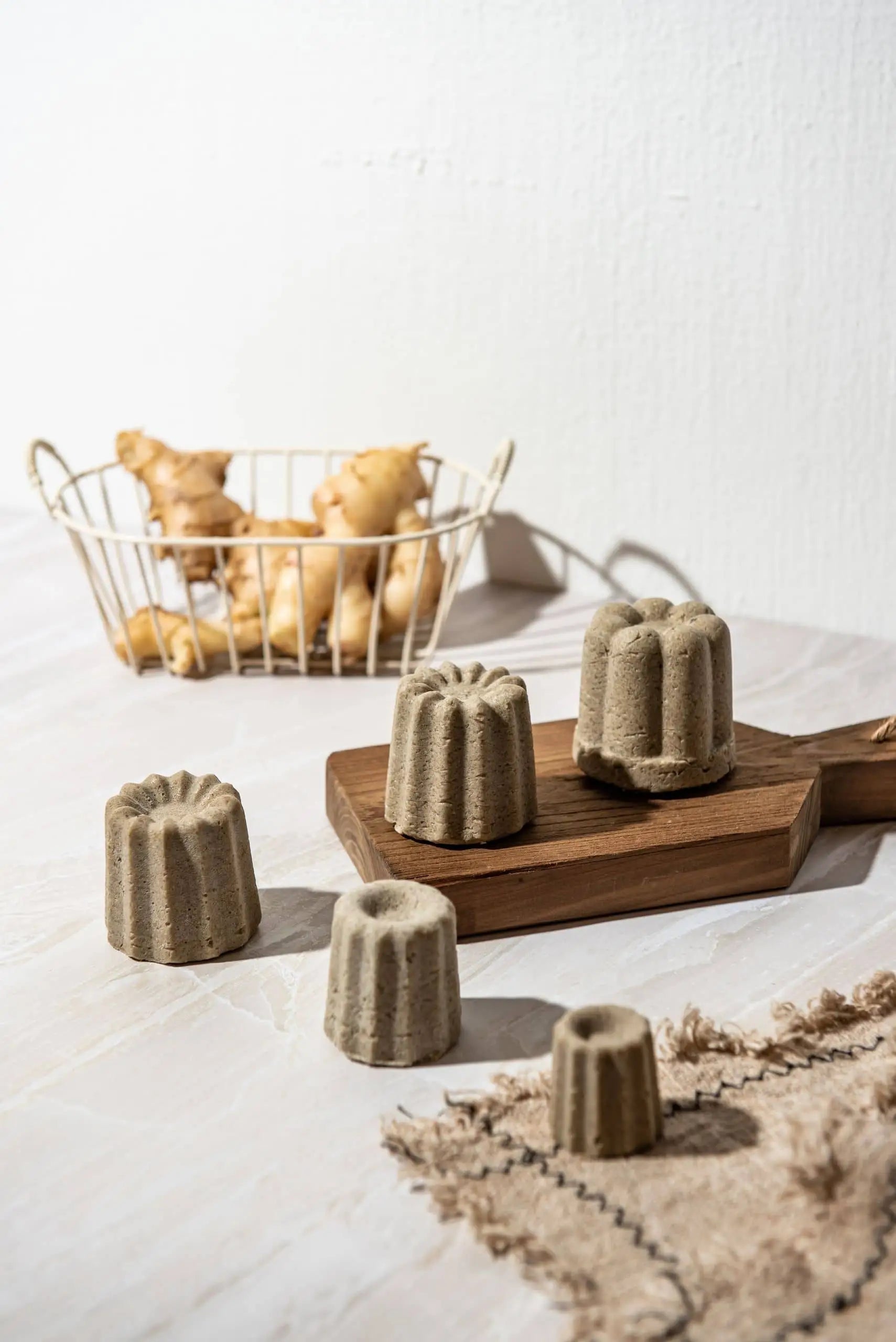 Four Oasis Beauty Kitchen Ginger Solid Shampoo bars (Midi Canele) rest on a wooden board with fresh ginger root in the background, emphasizing the benefits of organic ginger oil and herbs for hair growth.