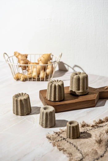 Four Oasis Beauty Kitchen Ginger Solid Shampoo bars (Midi Canele) rest on a wooden board with fresh ginger root in the background, emphasizing the benefits of organic ginger oil and herbs for hair growth.