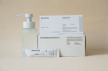 The Pass It On 0.02 Refillable Hand Wash Set, Single Pack - Marine Moss by Pass It On features a pump bottle, powder sachet, and “Plusit On.” box in sleek white packaging for a minimalist, sustainable hand washing routine.
